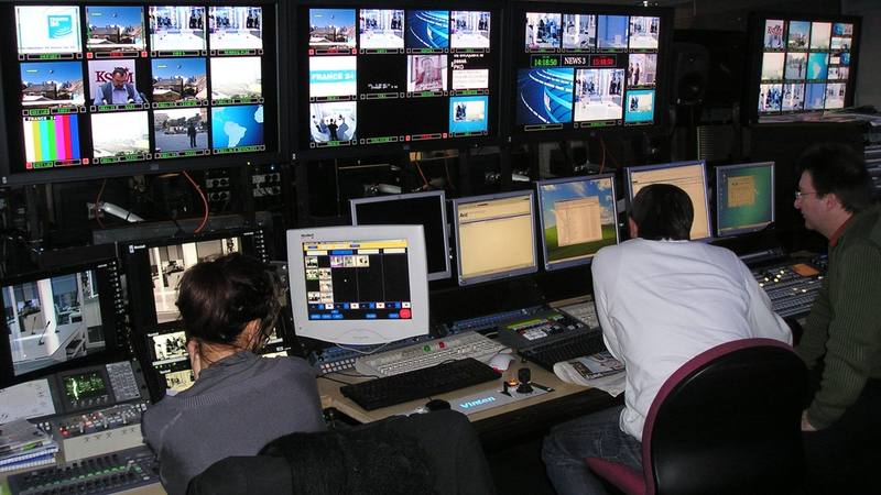 Une régie de télévision avec ses murs d'écrans de contrôle et trois techniciens assis devant leurs pupitres