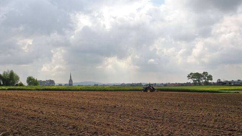 Champ labouré et clocher de village dans la campagne du Nord de la France, photo d'illustration sans lien direct avec le tournage