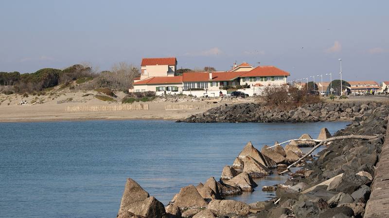 Vue de La Tamarissière à Agde, avec la plage, la jetée et des bâtiments face à la mer (photo d'illustration du quartier, pas du restaurant de l'émission)