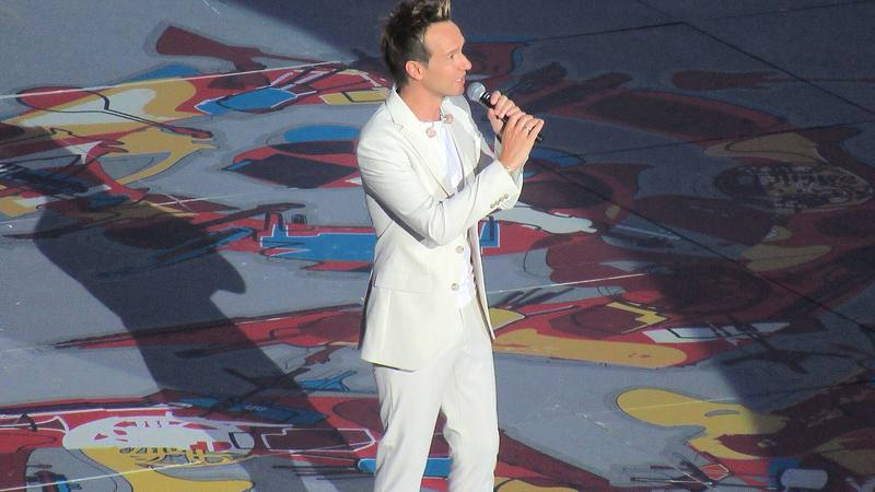 Cyril Féraud en costume clair, micro à la main, lors du spectacle Horizons Celtique au Festival interceltique de Lorient en 2024