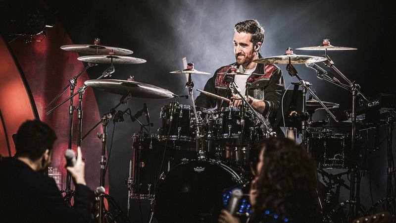 Le batteur de N'oubliez pas les paroles sur scène, dans la fumée et les projecteurs, lors de la tournée du jeu en 2022