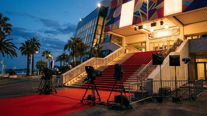Escalier de marches rouges devant un grand palais de congrès en bord de mer au crépuscule, photo d'illustration sans personne identifiable