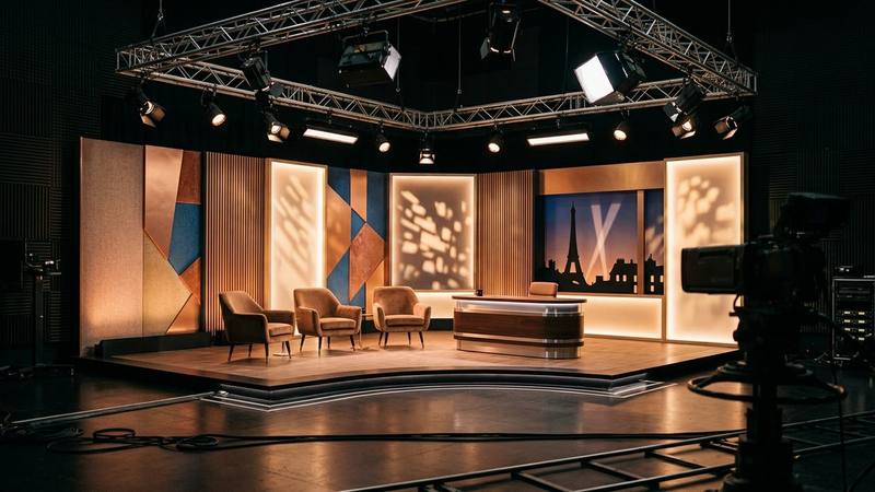 Plateau de talk-show de début de soirée, bureau et fauteuils sous des projecteurs, photo d'illustration sans personnalité identifiable