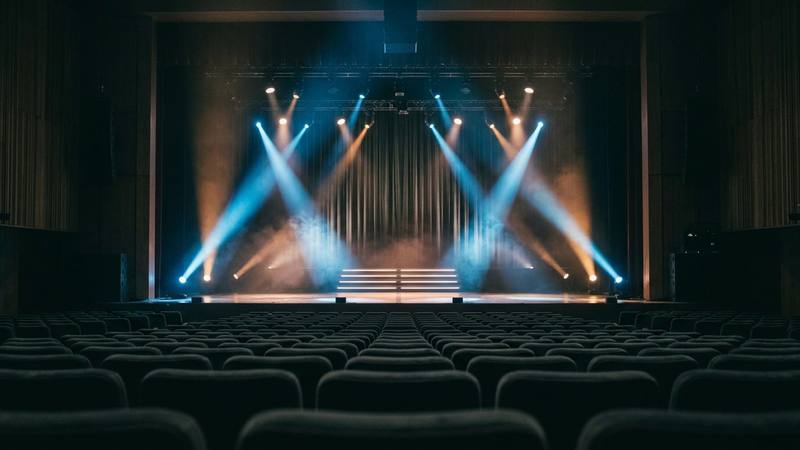 Grande scène de spectacle vide baignée de lumière bleue et ambrée, projecteurs braqués vers des marches centrales, photo d'illustration sans lien direct avec la Star Academy