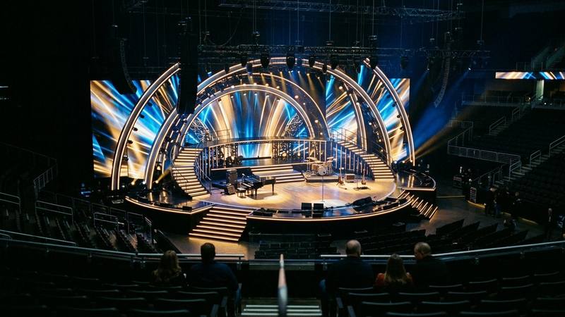 Grand plateau de télévision vu depuis les gradins, scène vide éclairée de projecteurs bleus et dorés avant un spectacle musical, photo d'illustration sans lien direct avec une émission précise