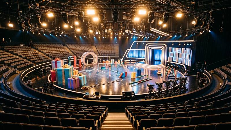 Grand plateau de télévision vide avant un prime, gradins du public et projecteurs allumés, photo d'illustration sans personnalité identifiable