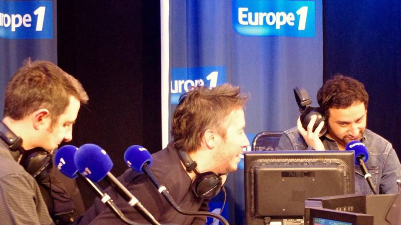 Cyril Hanouna, à droite, casque sur l'oreille, lors d'une émission de radio sur Europe 1 en janvier 2014. © Julien Morvan / Wikimedia Commons