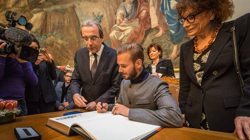 M. Pokora signe le livre d'or de la ville de Strasbourg en février 2014, coach de l'équipe victorieuse de The Voice Kids 2026. © Claude Truong-Ngoc, Wikimedia Commons (CC BY-SA 3.0)